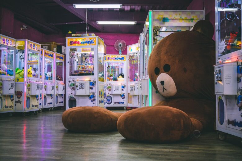 クレーンゲームの前に座る大きなクマのぬいぐるみ