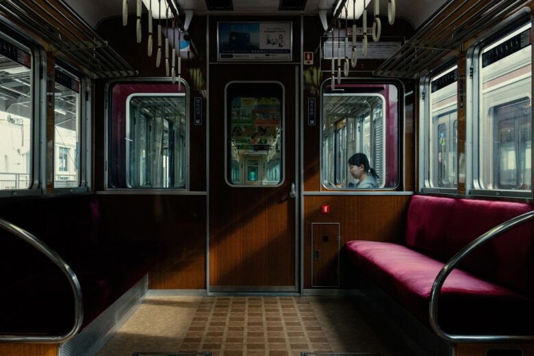 赤い座席が並ぶがらんとした電車の車内