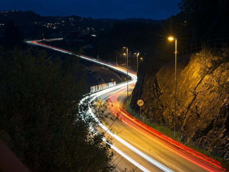 夜の山道に流れる車のライトの光跡