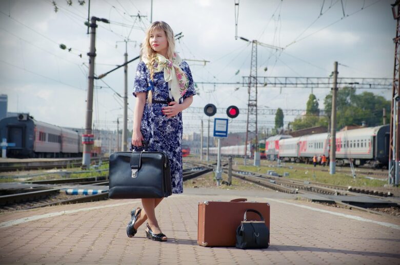駅のホームでトランクを持って立つ女性